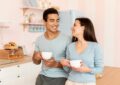 happy couple with coffee cups in kitchen