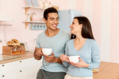 happy couple with coffee cups in kitchen